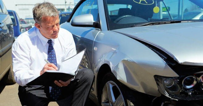 Insurance adjuster looking at a damaged car